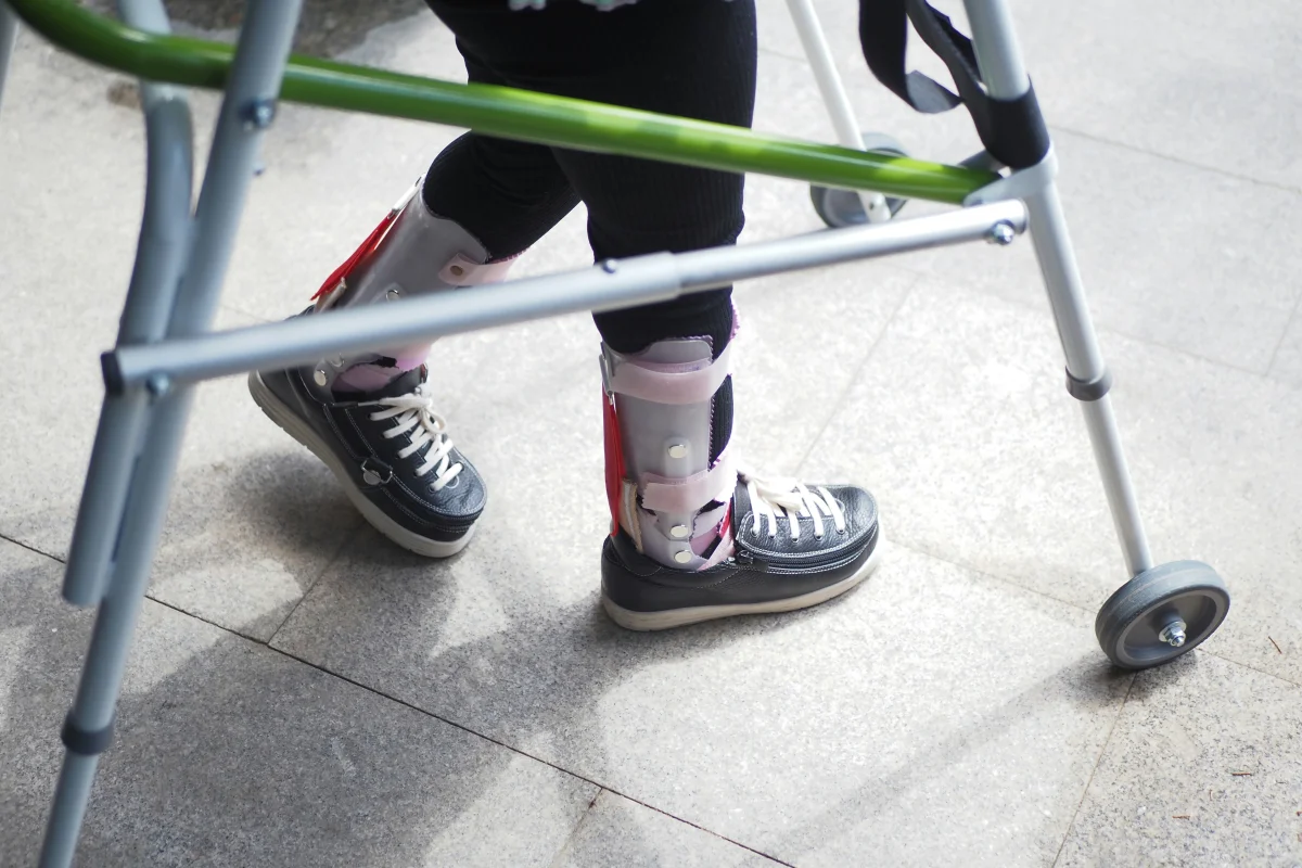 Child using a walking frame outdoors, representing disability accommodations in school settings