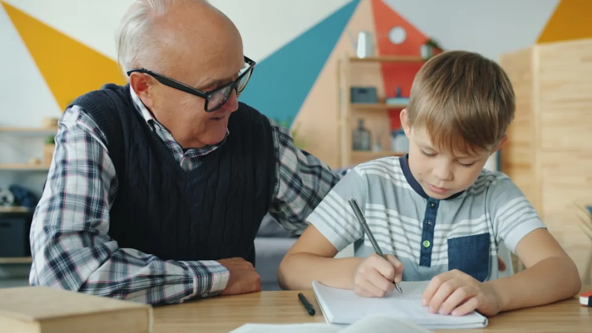 Grandfather helping grandson with homework at a table