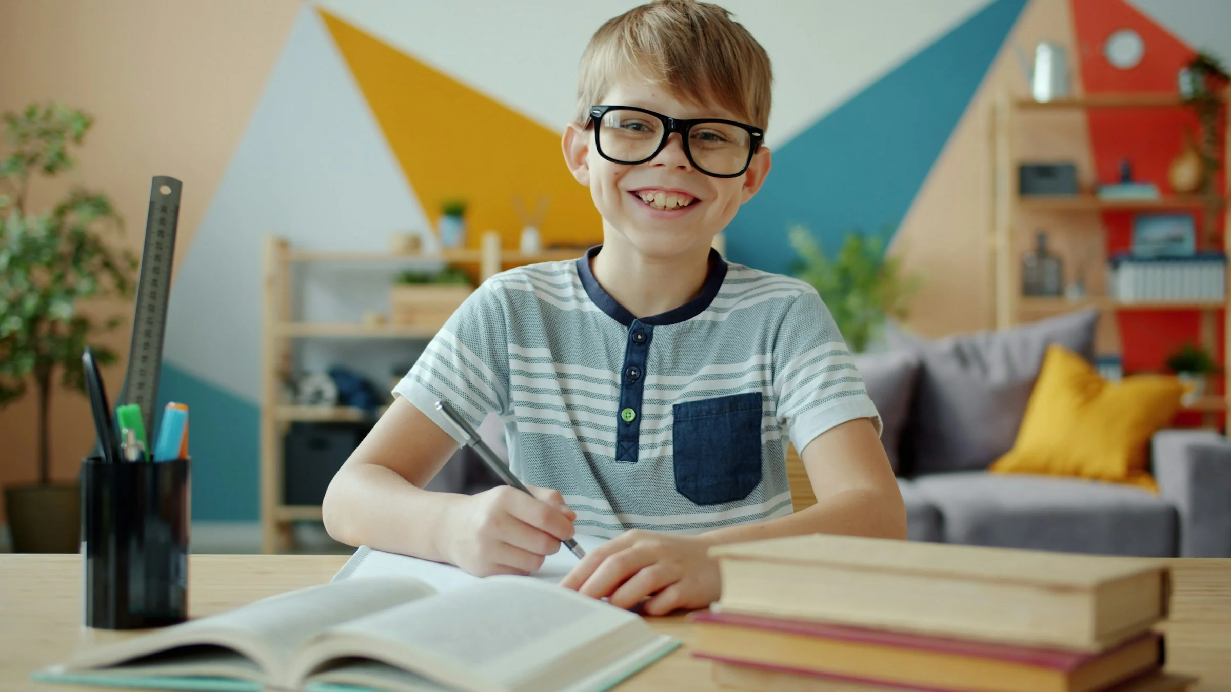 Smiling boy with glasses studying at desk