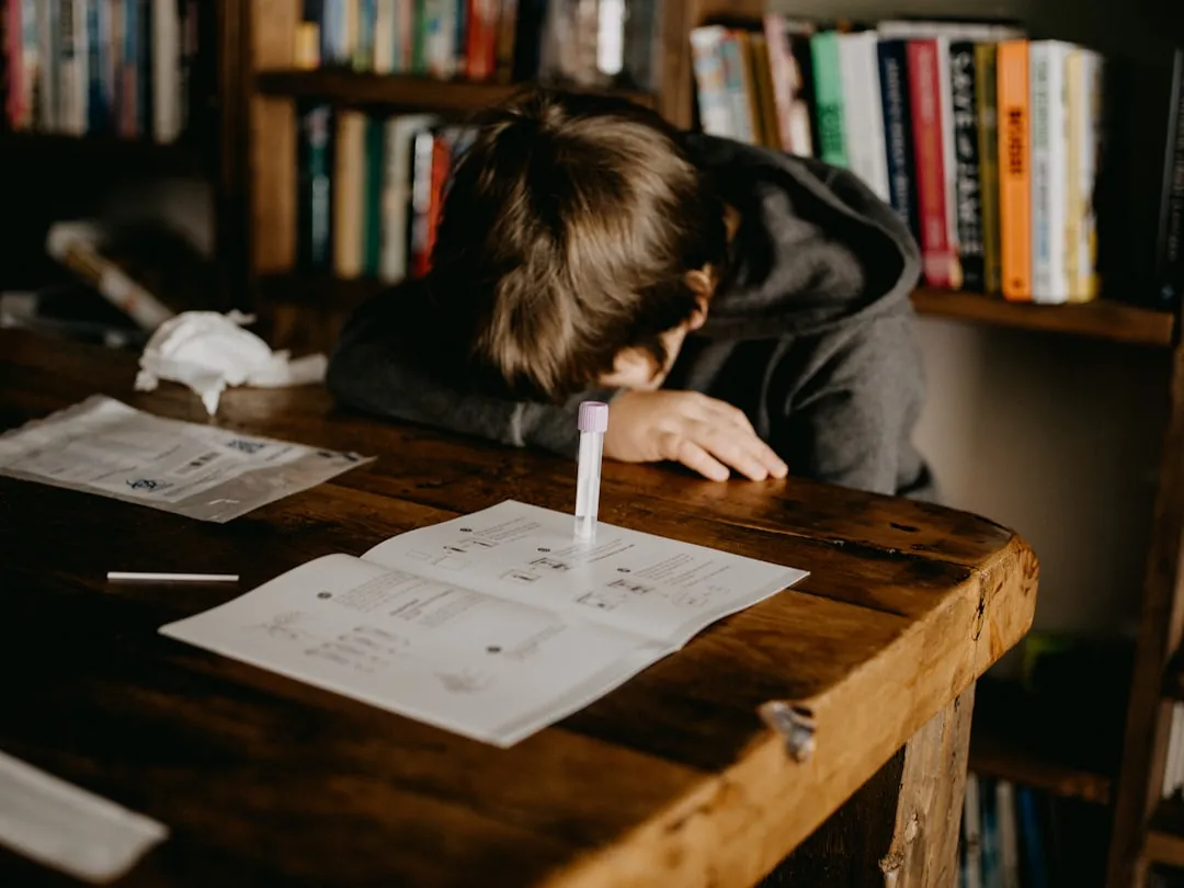 Boy in gray hoodie reading book on brown wooden table