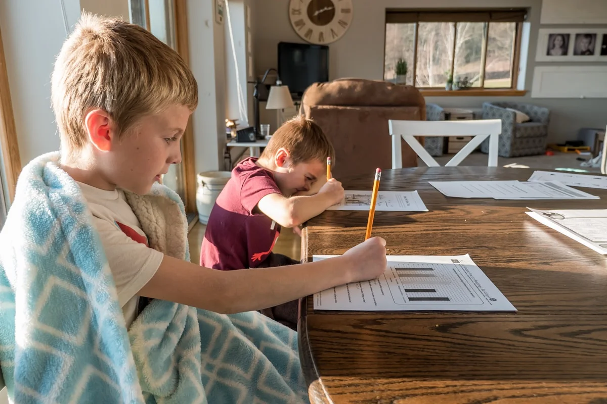 Boy in gray t-shirt reading a book intently, appearing thoughtful and engaged