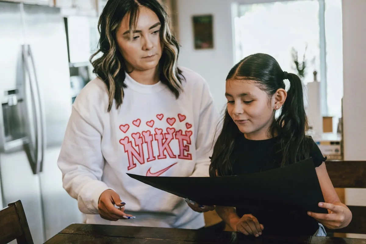Mother and daughter reviewing school documents together at kitchen table