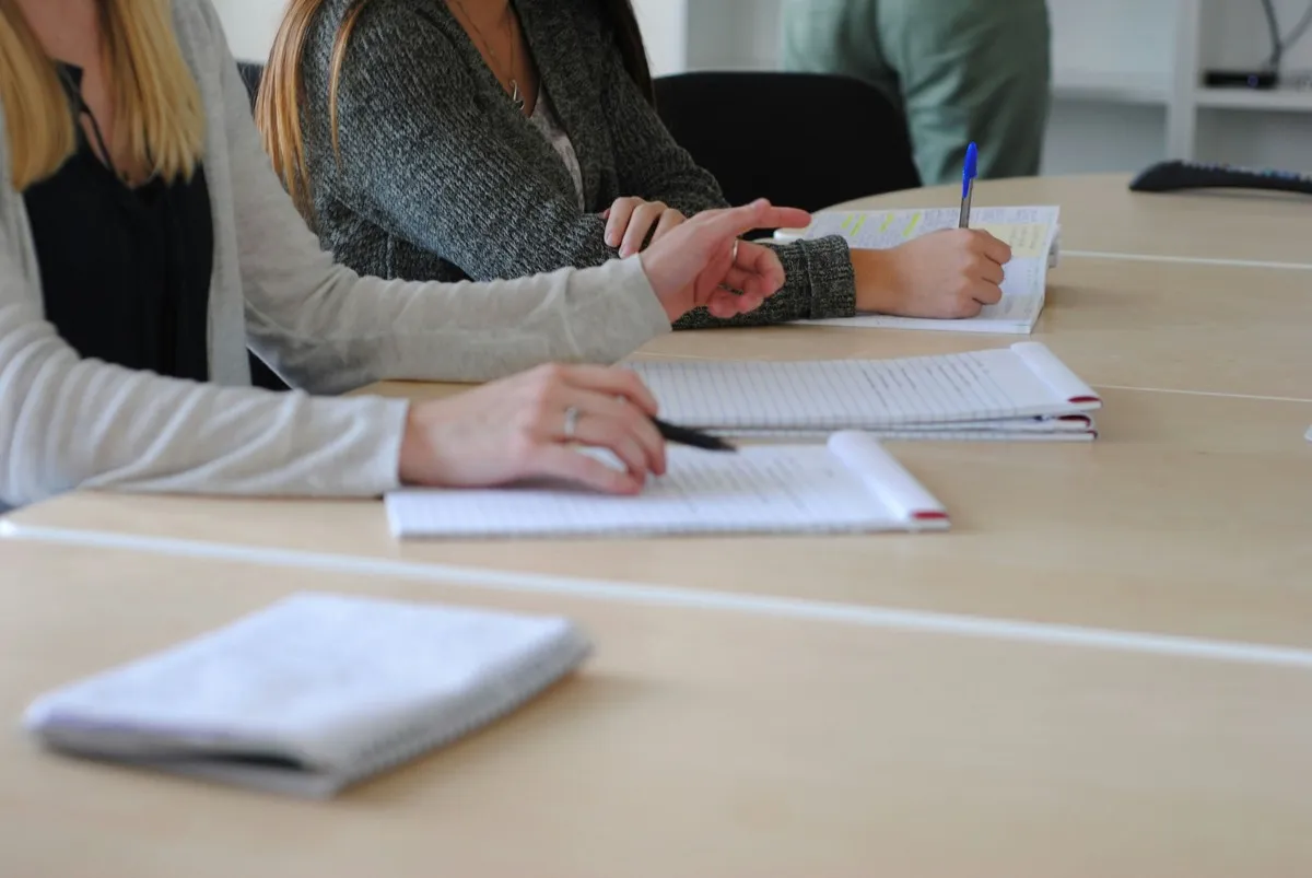 A woman writing on a piece of paper during a meeting