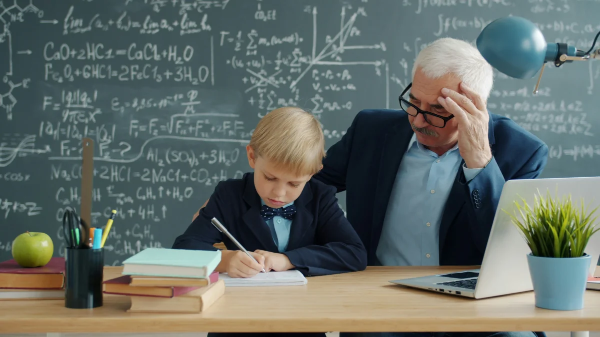 Adult supporting a child's learning at a classroom desk