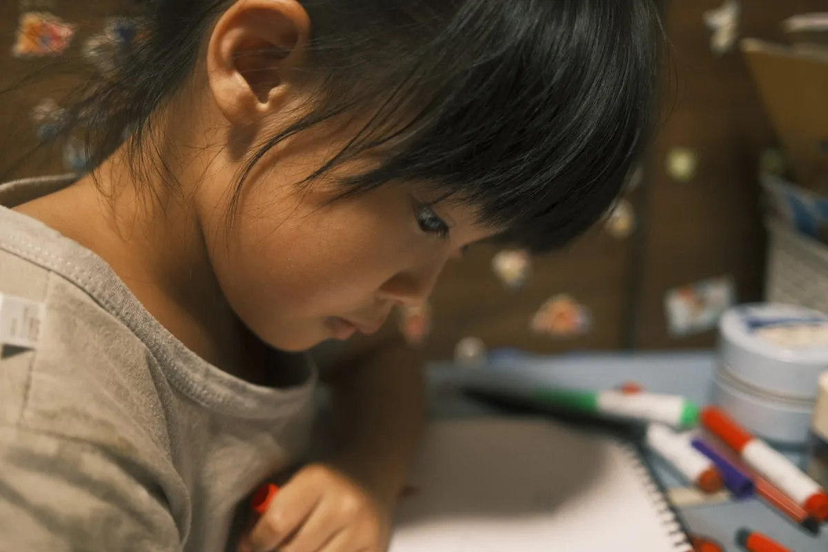 Girl in gray shirt sitting at desk looking thoughtful