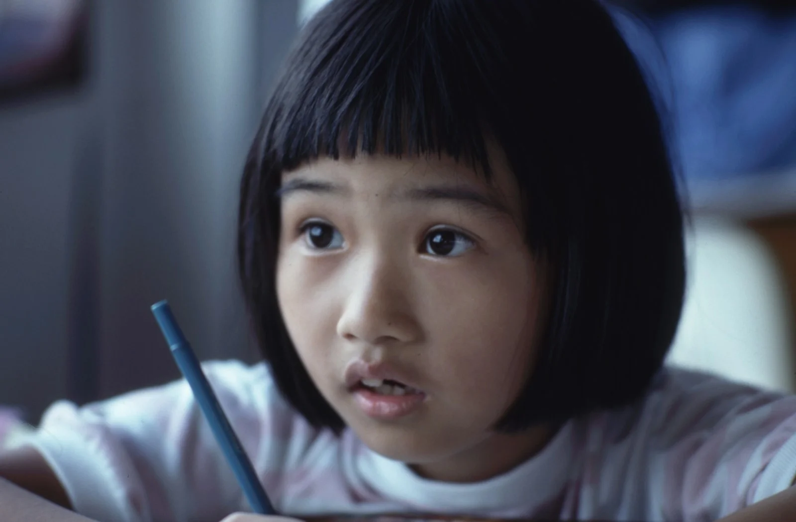 Girl holding a pen at a school desk, representing the focused but complex experience of twice-exceptional learners